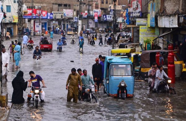 Commuters make their way through a flooded street during monsoon rainfall in Hyderabad, Pakistan, on July 24, 2022. (Akram Shahid / AFP via Getty Images)